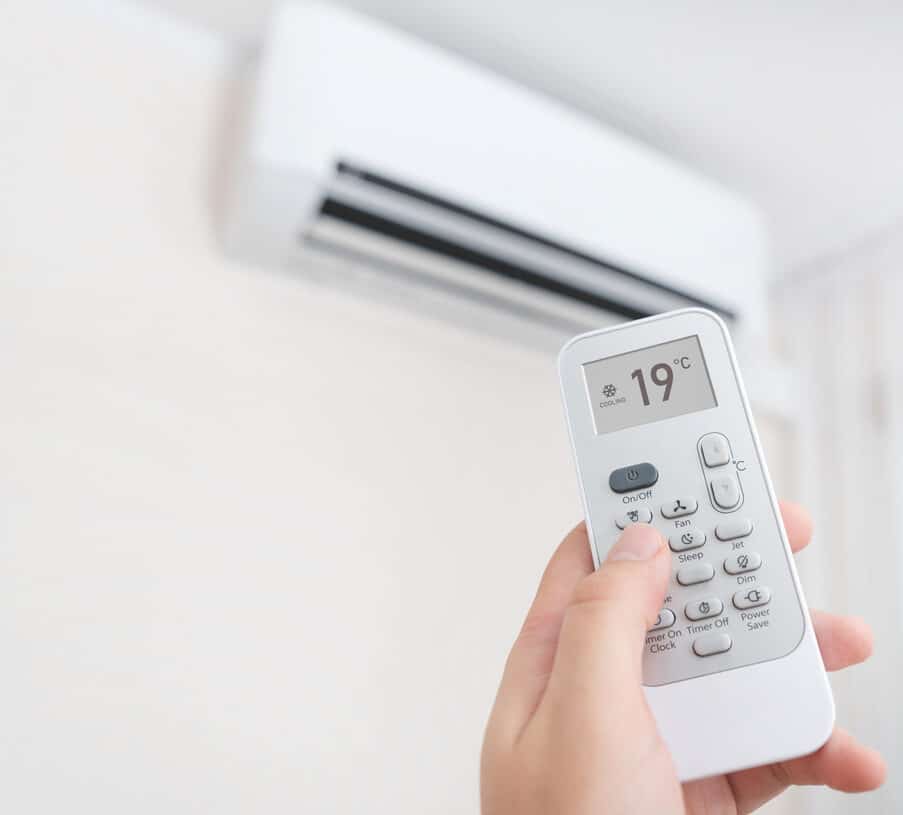 A ductless AC remote control being used to adjust temperature settings for optimal indoor comfort and energy efficiency.