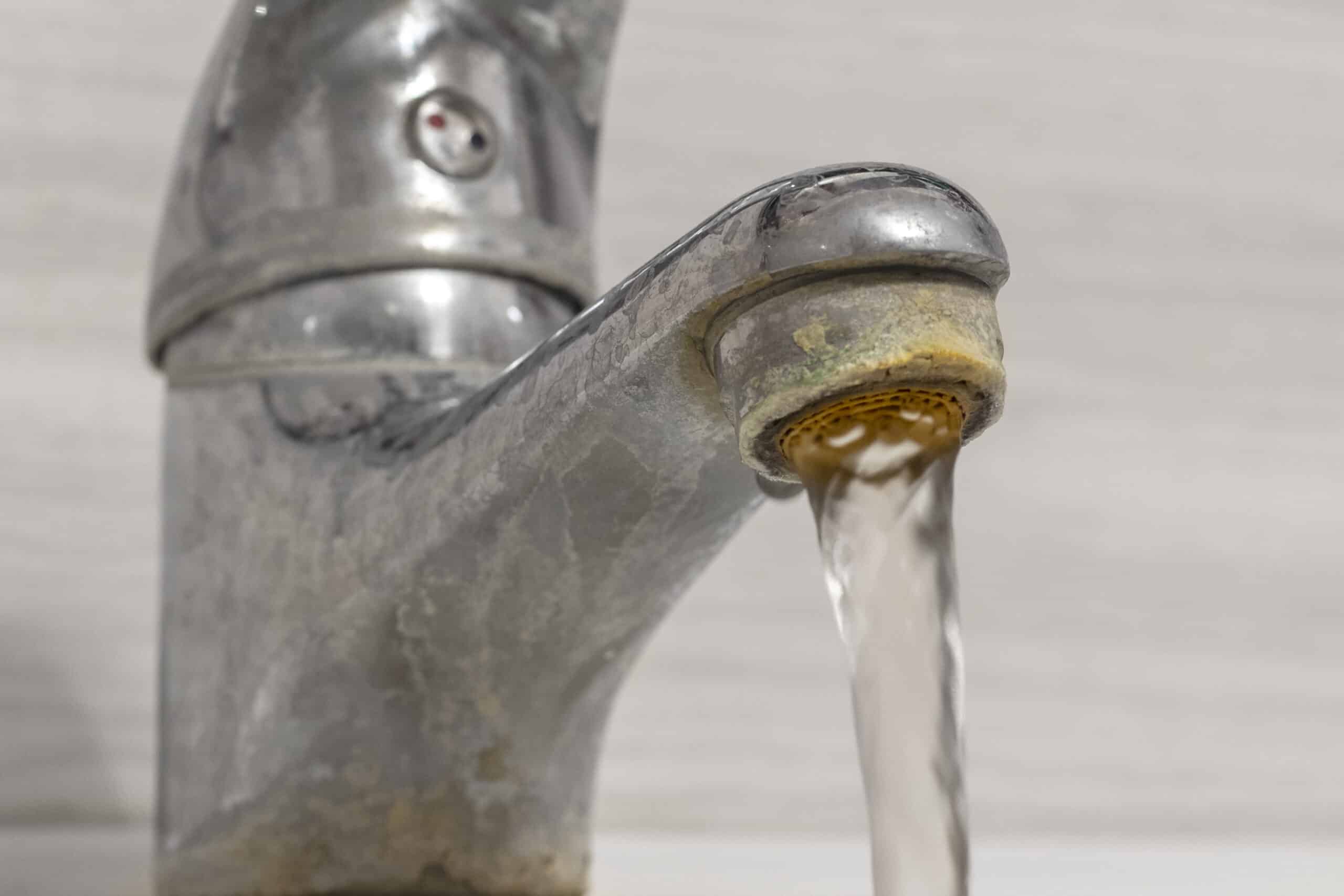 Close-up of hard water buildup on a running faucet